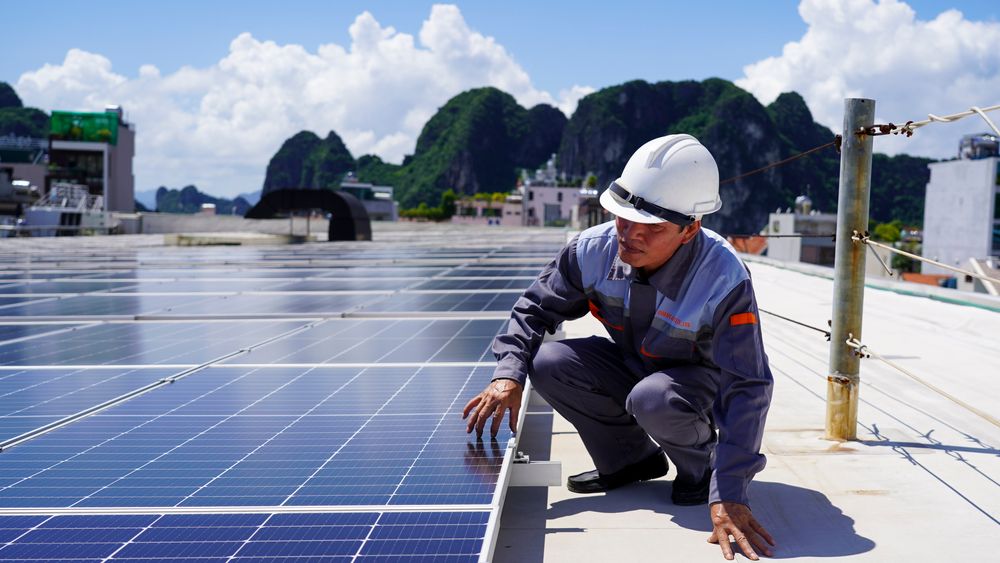 En mann vedlikeholder solcellepanelene på taket til GO-Supermarket i Ha Long City i Vietnam, der Norad har støttet et solcellekraftverk gjennom sin bedriftstøtteordning.