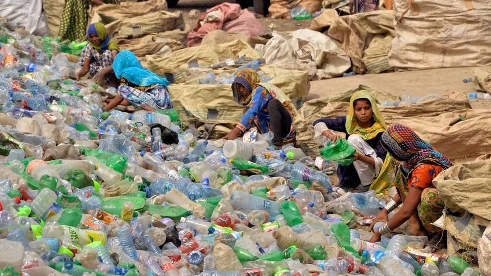 Pakistanske arbeidere sorterer tomme plastflasker ved en resirkuleringsfabrikk i Hyderabad.