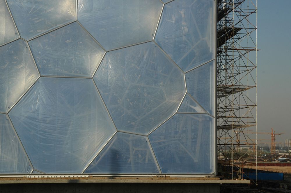 Hjørne av svømmehallen til sommer-OL i Beijing 2008. Bak den gjennomsiktige fasaden skimtes et omfattende fagverk. Ingen vinkler eller lengder er identiske.