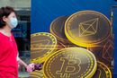 En kvinne passerer reklame for kryptovalutaen bitcoin i Hongkong. Utvinning av bitcoin krever enorme mengder energi er og er businessen er blitt en miljøversting.