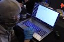 En maskert agent fra russiske FSB (føderal sikkerhetstjeneste) studerer en PC beslaglagt fra hackergruppen Revil etter en aksjon I januar 2022. Yaroslav Vasinsky ble arrestert i en annen aksjon.