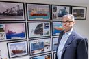 Administrerende direktør Svein Ringbakken i Det norske krigsforsikringsselskap for skib (DNK) foran en vegg med bilder fra kritiske situasjoner deres medlemmer har vært oppe i gjennom årene. 