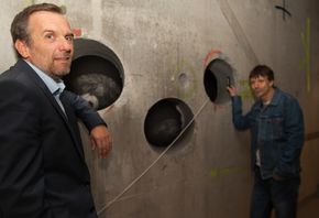 Leidulf Skjørestad (til venstre) og Ernst Olsen viser hullene i energisentralens betomgvegg. Her blir det plass til vannrørene som skal lede varme fra kloakken inn til varmepumpene, samt rør for elektriske ledninger. <i>Foto: Alf Bergin</i>