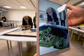 Når nettbrettet holdes opp mot kartet på bordet, dukker byen elevene har designet opp i 3D på nettbrett-skjermen – plassert inn i omgivelsene. <i>Foto:  Pia Eide</i>