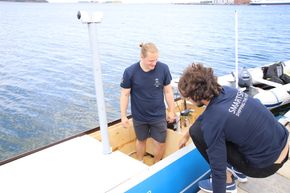 August Ekanger (t.v) og Jonas Hopsdal har brukt mye tid med programmering og  montering av utstyr og sensorer om bord i Yara Birkeland-modellen. Sementsekker er brukt for å stabilisere fartøyet.   <i>Foto: Tore Stensvold </i>