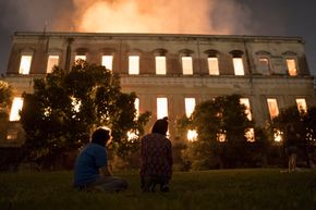 Folk ser på at flammene river ned det 200 år gamle nasjonalmuseet i Rio de Janeiro, Brazil søndag. <i>Foto:  Leo Correa / AP</i>