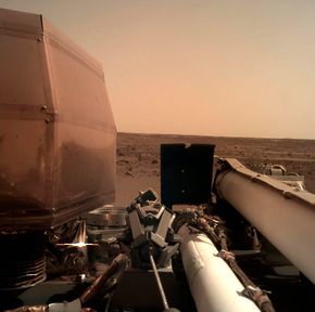 Dette bildet er tatt med et kamera som er montert på en av InSight-sondens robotarmer, og viser litt av landingsstedet til sonden. <i>Foto:  AP/NTB Scanpix</i>