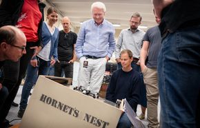 Petter Muren (i midten) studerer «Hornet's Nest», et automatisk innfangingssystem for droner, som fire studenter konstruerte i sommer. <i>Foto:  Eirik Helland Urke</i>