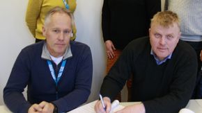 Seksjonsleder Jo Bernt Brønstad i Trøndelag fylkeskommune (foran t.v.) og daglig leder Per Martin Rønningen i HR Entrprenør AS signerer kontrakten om fornying av fv. 31 fra Røros til riksgrensen. <i>Foto:  Trøndelag fylkeskommune</i>