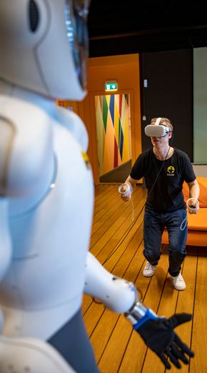 Bernt Børnich har tatt på seg VR-briller og kontrollere for å styre Eve til å bøye seg mot gulvet for å plukke opp ting. <i>Foto:  Jan Johannessen</i>