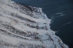 Et snøskred er løst ut med sprengladning fra helikopter ved Singla. Skredet har passert fylkesveien og havnet i sjøen. <i>Foto:  Troms fylkeskommune</i>