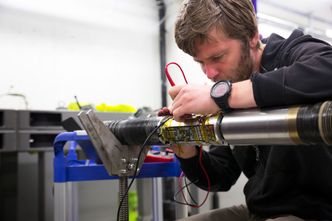 Tester: Softwareutvikler Simen Didden Dovland sjekker elektronikken før nok en runde med høy vibrasjons- og sjokktesting. Utstyret testes til det ødelegges, så de skal vite hvor grensen går. Foto: Mona Strande