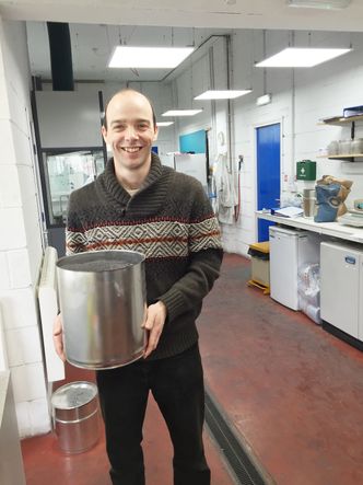 Bøtta full: Dr. Simon Broughton på laben til Grapithene Ltd viser fram en bøtte med grafén-derivat. Hver dag produseres det rundt seks kilo grafén ved fabrikken i North Lincolnshire. Foto: Privat