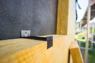 Etterisolering med de spesielle veggplatene gjøres tett-i-tett, og holdes fast med små plastfester. Foto: Paal-André Schwital