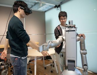 Masterstudenten Akio Shigekane og Yuta Watanabe, sammen med en robot som kan bidra innen pleie. Foto: Nils Olav Mevatne