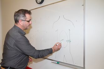 Øyvind Stavedal viser hvordan en port blir operert inn hos pasienten, og at en slange fører sensoren og insulinet inn i bukhulen. Hvor i bukhulen dette skal plasseres er ennå ikke besluttet, heller ikke hvor stor avstanden må være mellom sensor og der insulinet pumpes ut i kroppen. Foto: Joachim Seehusen