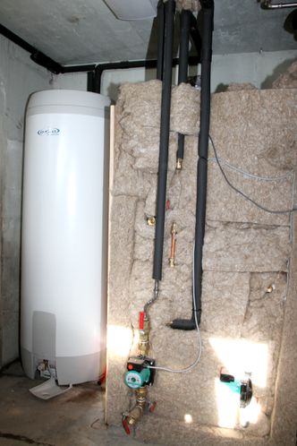 Ved siden av varmtvannsberederen er det installert en isolert tank på 300 liter. Den fylles med vann som er forvarmet gjennom rør støpt inn i masseovnen. Varmtvannsberederen får vann inn som allerede holder godt over 30 grader. Foto: Joachim Seehusen