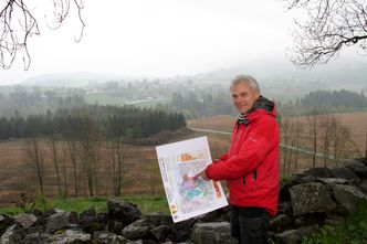 Regiongeolog Sven Dahlgren med foreldete geologiske kart som ikke kan brukes som grunnlag for å fastslå hvor mye sjeldne jordarter Fensfeltet inneholder. Dahlgren etterlyser mer omfattende kartlegging av mineralressurser, ikke bare på Fensfeltet men i hele landet. Bildet er tatt fra Holla kirkeruin, viser deler av Fensfeltet, i tåken i bakgrunnen ligger Gruveåsen der Fen Minerals har rettigheter. Foto: Joachim Seehusen