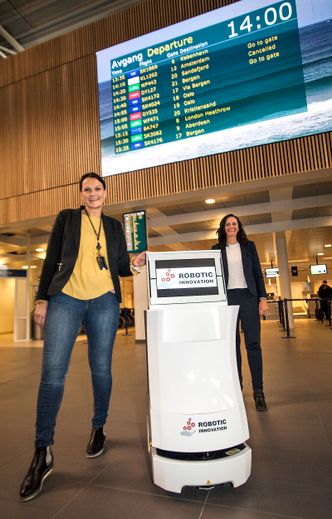 – En slik robot kan være til god hjelp for både passasjerer og ansatte på Sola. Dessuten er den en liten attraksjon i seg selv, sier Ellen Ringen (t.v.), Avinors leder for terminaltjenester på Sola. Annette Anfinnsen gleder seg over publikums nysgjerrighet på roboten som trillet inn i avgangshallen. Bilde:  Alf Bergin