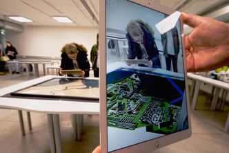 Når nettbrettet holdes opp mot kartet på bordet, dukker byen elevene har designet opp i 3D på nettbrett-skjermen – plassert inn i omgivelsene. Foto: Pia Eide