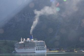 Cruiseskip ved kai i Flåm. Eksosen legger seg som en blåhvit dis. Foto:  Tore Stensvold