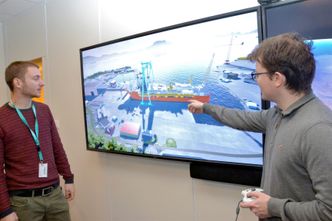 Ved hjelp av spillkonsoll og spillmotor kan de to som utgjør gruppen for utvikling av animasjoner hos Kværner på Stord bevege seg rundt på skjermen i den digitale verftsverden de selv skaper. Fra venstre: Simen Leth og Thomas Gram. Foto: Thomas Førde