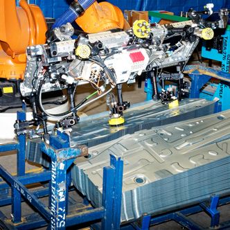 En robot flytter ferdige stålplater frem og tilbake mellom to stabler. Det er en forberedelse til produksjonen av ID og ingeniørene må være sikre på at elektromagnetene plukker med seg kun én plate hver gang, og at den sitter godt. Det måles, justeres, måles på nytt og testes på alle mulige vis. Foto:  Joachim Seehusen