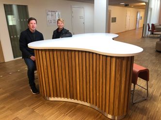 Anders Bru fra Glamox og Kari Hornmoen fra Multiconsult sitter rundt en møteplass i korridoren på akuttpost B. Foto:  Tuva Strøm Johannessen