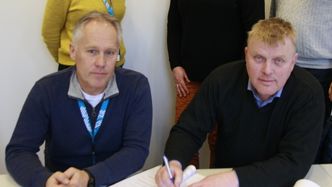 Seksjonsleder Jo Bernt Brønstad i Trøndelag fylkeskommune (foran t.v.) og daglig leder Per Martin Rønningen i HR Entrprenør AS signerer kontrakten om fornying av fv. 31 fra Røros til riksgrensen. Foto:  Trøndelag fylkeskommune