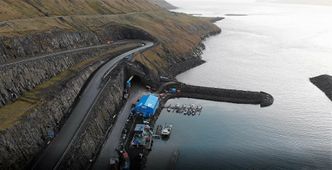 Tunnelinslaget ligger ved fergeleiet som i dag er endestasjon for bilveien til Sandoy. Tettstedet Kirkebø med Magnuskatedralen skimtes helt øverst i bildet. Foto:  NCC