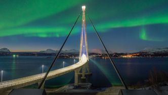 Hålogalandsbrua opplyst av både kunstig diode-lys og naturens fargepalett. Foto: Robin Lund, Statens vegvesen