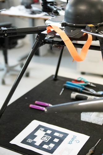 Det lille kameraet på undersiden av dronen (under oransje bånd), brukes når dronen fikseres til en QR-kode på et bevegelig landingssted. Ved å hivkompensere for underlagets bevegelser, for eksempel i en båt på sjøen, lander dronen mykere. Foto:  Alf Bergin