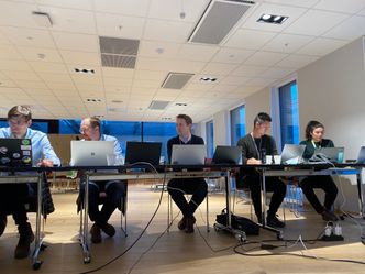 – Under øvelsen fant vi nye sårbarheter og kreative måter for å beskytte kundene vi jobber for. Det viktigste er kanskje samholdet vi skaper. Gjensidig tillit mellom teamene er viktig for å skape et trygt miljø hvor folk får muligheten til å utvikle seg samtidig som de vet at alle heier på hverandre, forteller Jan Henrik Schou Straumsheim (midt i bildet). Nico og fem andre var med digitalt på skjermer.