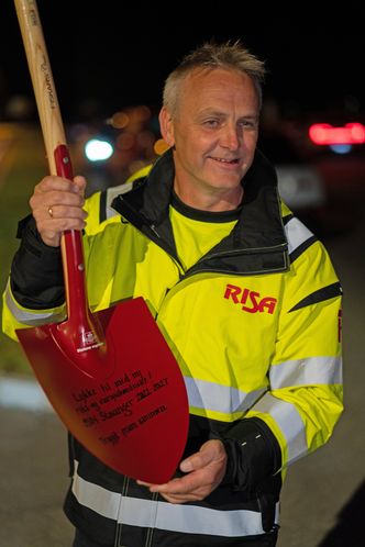 Vegdriftssjef Erlend Aksnes i Risa AS med spaden med påskriften «Lykke til med ny riks- og europavegkontrakt! 9301 Stavanger 2022-27. Trygt fram sammen». Sistnevnte er et av Vegvesenets slagord, og navnet på en Vegvesenets nasjonale kampanjer for trafikksikkerhet. Foto: Daniel Skavland, Risa AS Vegdriftssjef Erlend Aksnes i Risa AS med spaden med påskriften «Lykke til med ny riks- og europavegkontrakt! 9301 Stavanger 2022-27. Trygt fram sammen». Foto: Foto:  Daniel Skavland, Risa AS