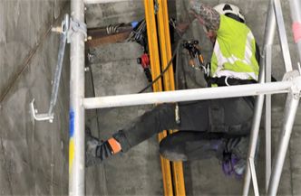 Arbeiderne må være litt apekatt for å få jobben gjort. Her monteres løpeskinne for talje og vinsj i taket på det ene forankringskammeret. Taket det jobbes under har 45 graders vinkel. Foto:  Knut Haarvik/Statens vegvesen