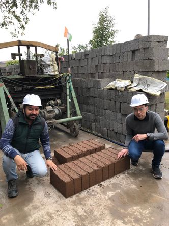 Sandeep Malhotra (Indo Enviro Integrated Solutions Limited) og Christian J. Engelsen (Sintef) viser frem prøveproduksjon av betongblokker med ny type resirkulert tilslag fra Goa. Foto: Sintef