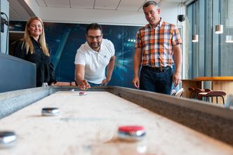 Maren-Elise, Sukhmeet og Hans-Petter tar seg et lite avbrekk med shuffleboard. Foto: TUM Studio