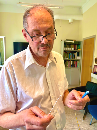 Martin Landrø viser størrelsen på de fiberoptiske kablene forskere brukte for å oppdage hvaler, selv når de ikke laget lyd. Foto: Nancy Bazillchuk/NTNU