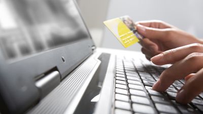 Person som taster inn kredittkortinformasjon på en laptop.