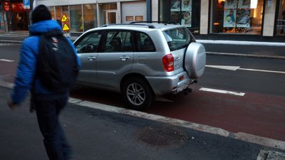 En sølv RAV 4 er parkert mot kjøreretningen i et klart oppmerket rødt sykkelfelt i Kongens Gate i Oslo sentrum. En person passerer på fortauet.