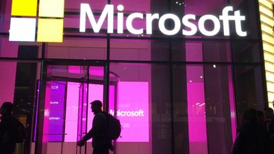 Silhuett av person foran vinduer med Microsoft-logoer.