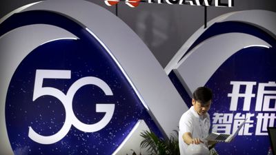 Mann foran en stor 5G-logo og en Huawei-logo.
