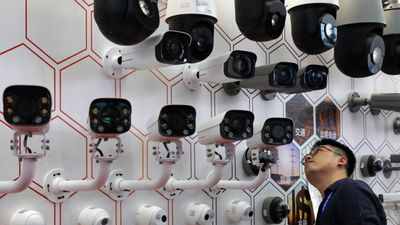 En mann titter på Kinas telekomgigant Huaweis kameraer i Shenzhen. Overvåkingsindustrien i landet er en enorm næring og USA har vært med som aktør helt fra begynnelsen og gjort gode penger.