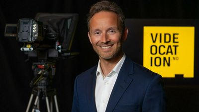 Marius Olsen smiler mellom et videokamera og en gul Videocation.no-logo.