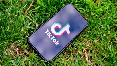 TikTok-logoen på en smartmobil som ligger på en gressplen.
