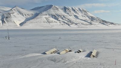 Feltforsøk på Svalbard undersøker potensialet og utfordringer for bakkemonterte solkraftverk. Her ser vi anlegget tidlig på våren når strømproduksjonen akkurat har begynt, men en rad har blitt delvis begravet av snøfonner.