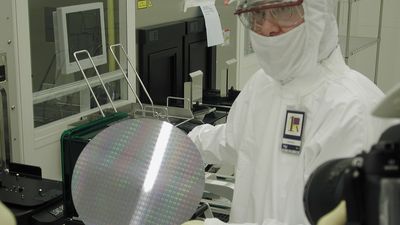 En fabrikkarbeider ved en av Intels fabrikker viser frem en silisiumskive (wafer).