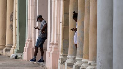 Et par innbyggere i Havana som bruker mobiltelefon med forhåndsbetalt tilgang til wifi-forbindelse.