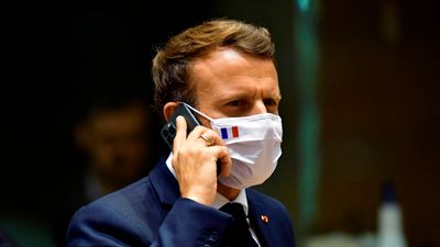 Frankrikes president Emmanuel Macron, her avbildet med ansiktsmaske og mobiltelefon.