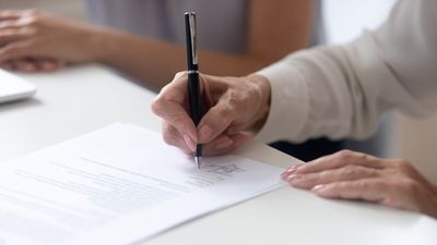 en kvinnehånd som holder en penn i ferd med å  underskrive en kontrakt